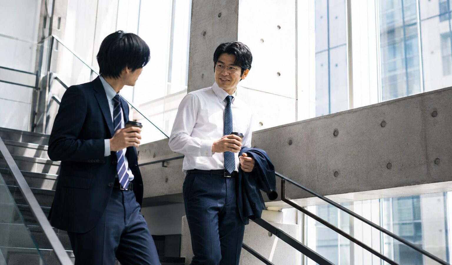 職場の同僚と階段を降りなががら、打ち合わせする40代男